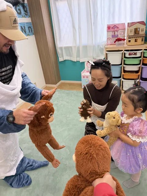 ピーカブーのハロウィンで、先生やお母さんと一緒にぬいぐるみを持って遊ぶプリンセスのドレスの女の子