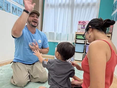 Peekabooクラスで先生とハイタッチをする男の子とお母さん