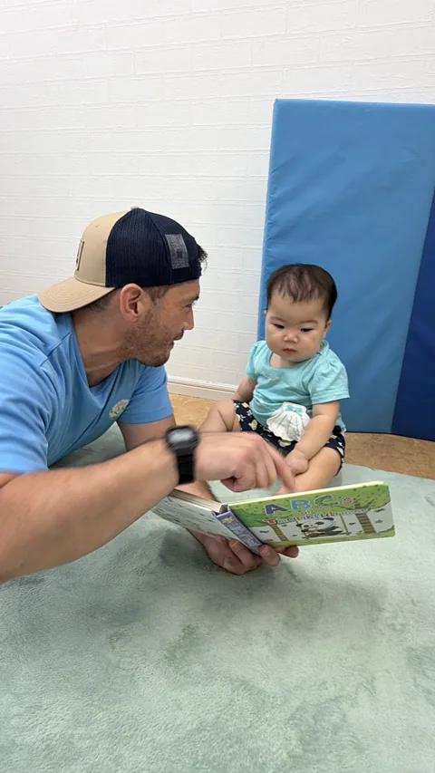プリスクールで先生に絵本を読んでもらう赤ちゃん