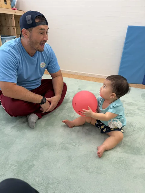 プリスクールで先生と赤いボールで遊ぶ赤ちゃん
