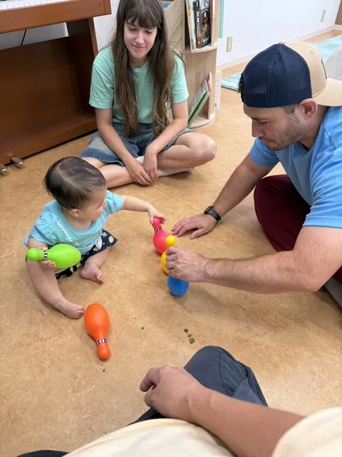 プリスクールで先生とボウリングのおもちゃで遊ぶ赤ちゃん