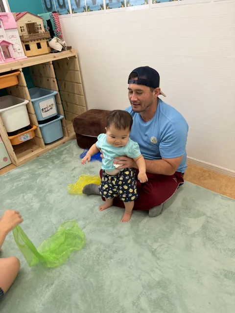 プリスクールで先生と一緒にスカーフ遊びを楽しむ赤ちゃん