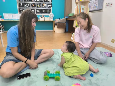 プリスクールで先生に見守られながらおもちゃの車で遊ぶ赤ちゃん