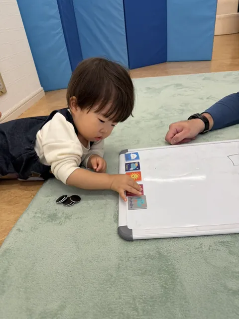 「Snowy」「Thunder」など英語の天気カードをホワイトボードに並べる子ども