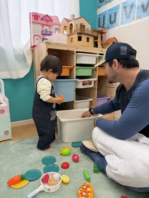 先生と一緒に、おままごとの道具をお片づけする子ども
