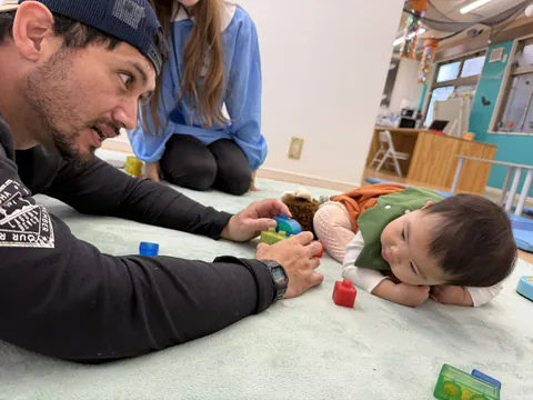 先生たちと一緒に、カラフルなブロックで遊ぶ赤ちゃん