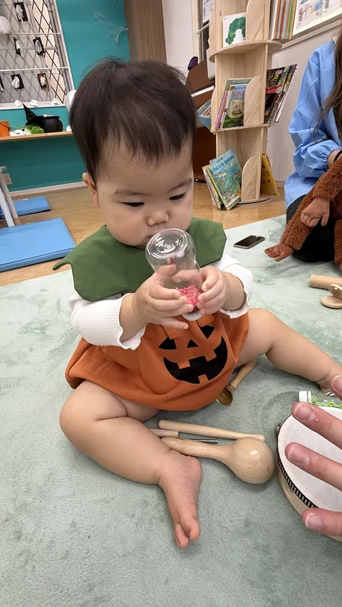 ビーズの入ったシェイカーボトルを両手で持って見つめる赤ちゃん