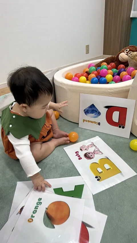 「Orange」や「Diamond」のアルファベットカードに手を伸ばす赤ちゃん