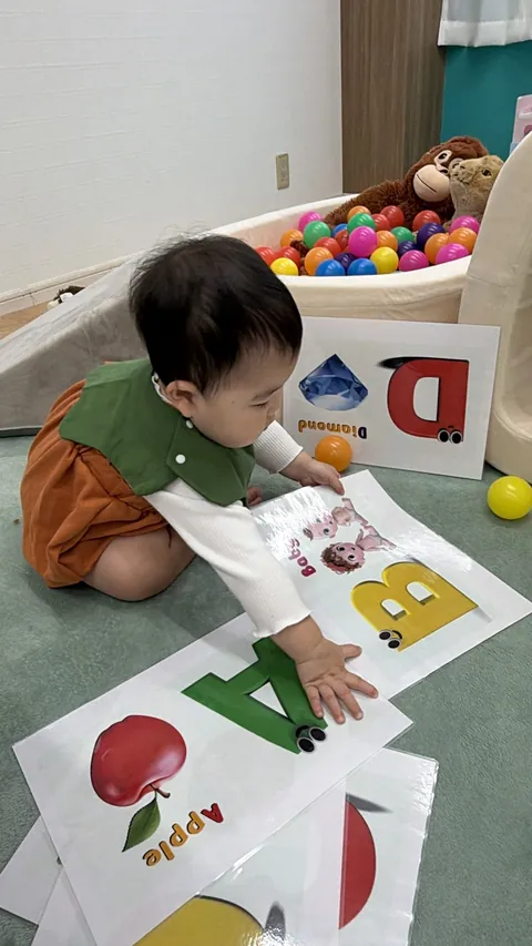 「Apple」のアルファベットカードにタッチする赤ちゃん