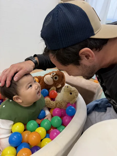 ボールプールの中で、先生と顔を見合わせて笑う赤ちゃん