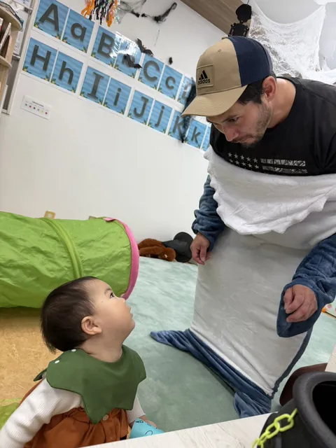 サメの着ぐるみの先生を見上げる赤ちゃん