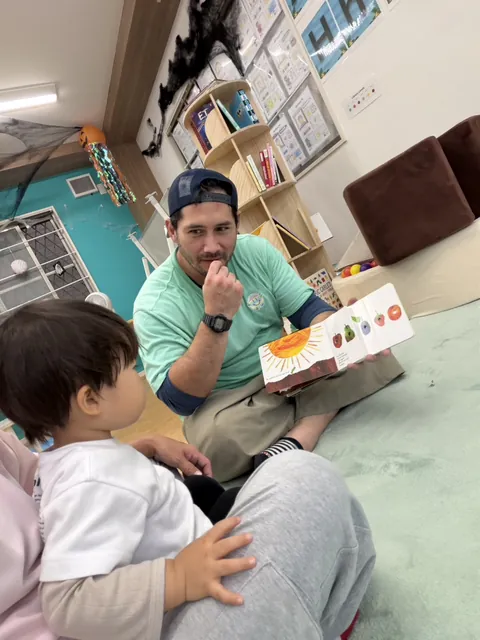 プリスクールで先生に「はらぺこあおむし」の絵本を読んでもらう赤ちゃん