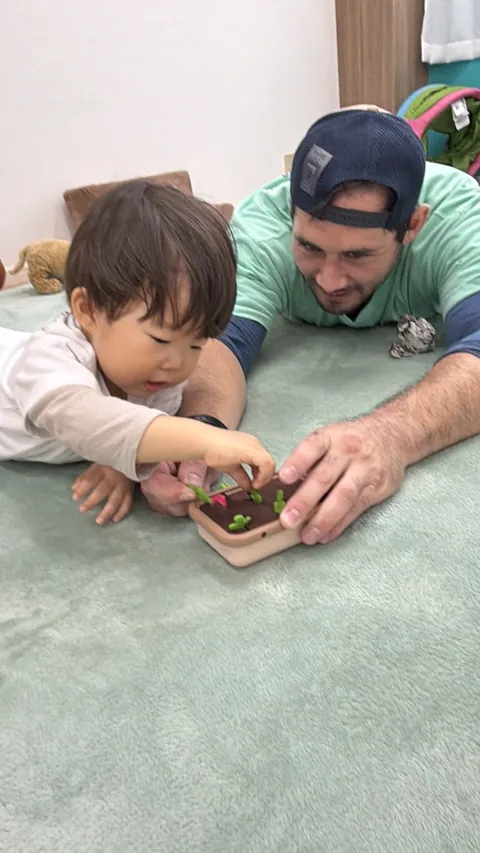 プリスクールで先生と野菜の収穫おもちゃで遊ぶ赤ちゃん