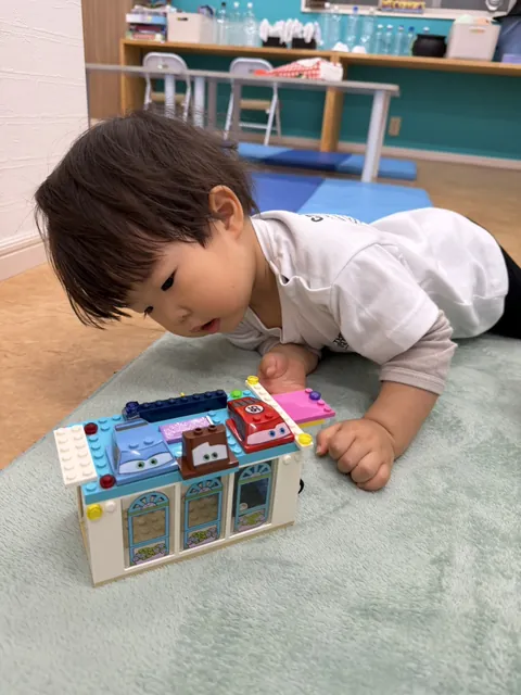 プリスクールでブロックのおもちゃをのぞきこんで遊ぶ赤ちゃん