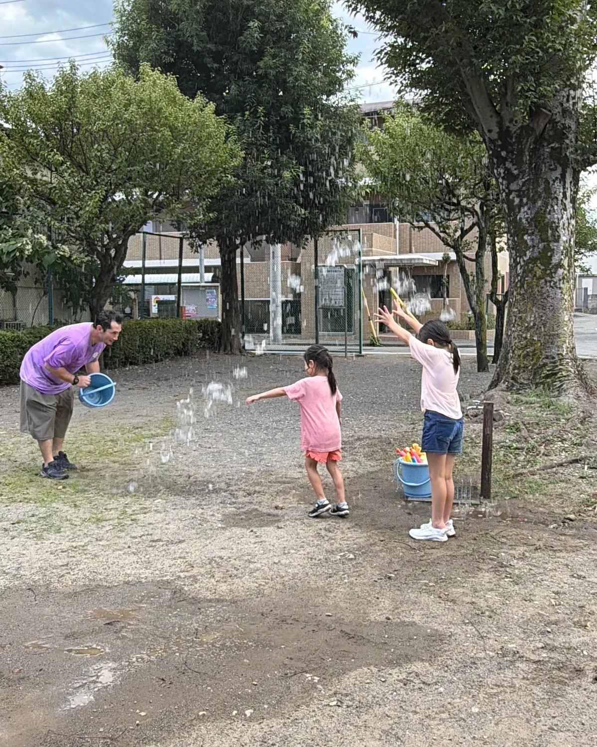 ホーリーをテーマに屋外で水遊びをする子どもたちと先生