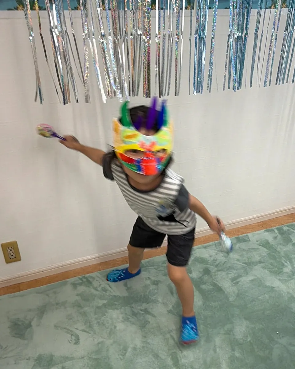 手作りのカーニバルマスクを着けて踊る子ども